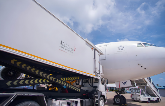 Maldives Inflight Catering truck branded by Montpellier Creative supplying an aircraft on the tarmac under a bright blue sky.