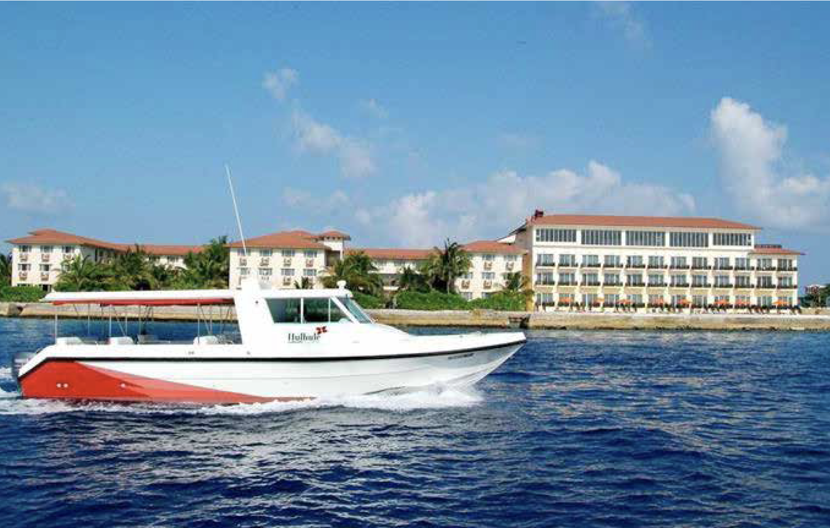 Branded water taxi for Hulhule Island Hotel featuring logo and livery designed by Montpellier Creative, with the hotel visible in the background across the turquoise waters of the Maldives