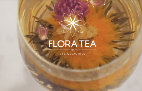 Ecommerce product showcase for Flora Tea, featuring elegant packaging and a blooming ‘Heart’s Desire’ green tea flower in a glass, with rose and lily ingredients and Great Taste award badge