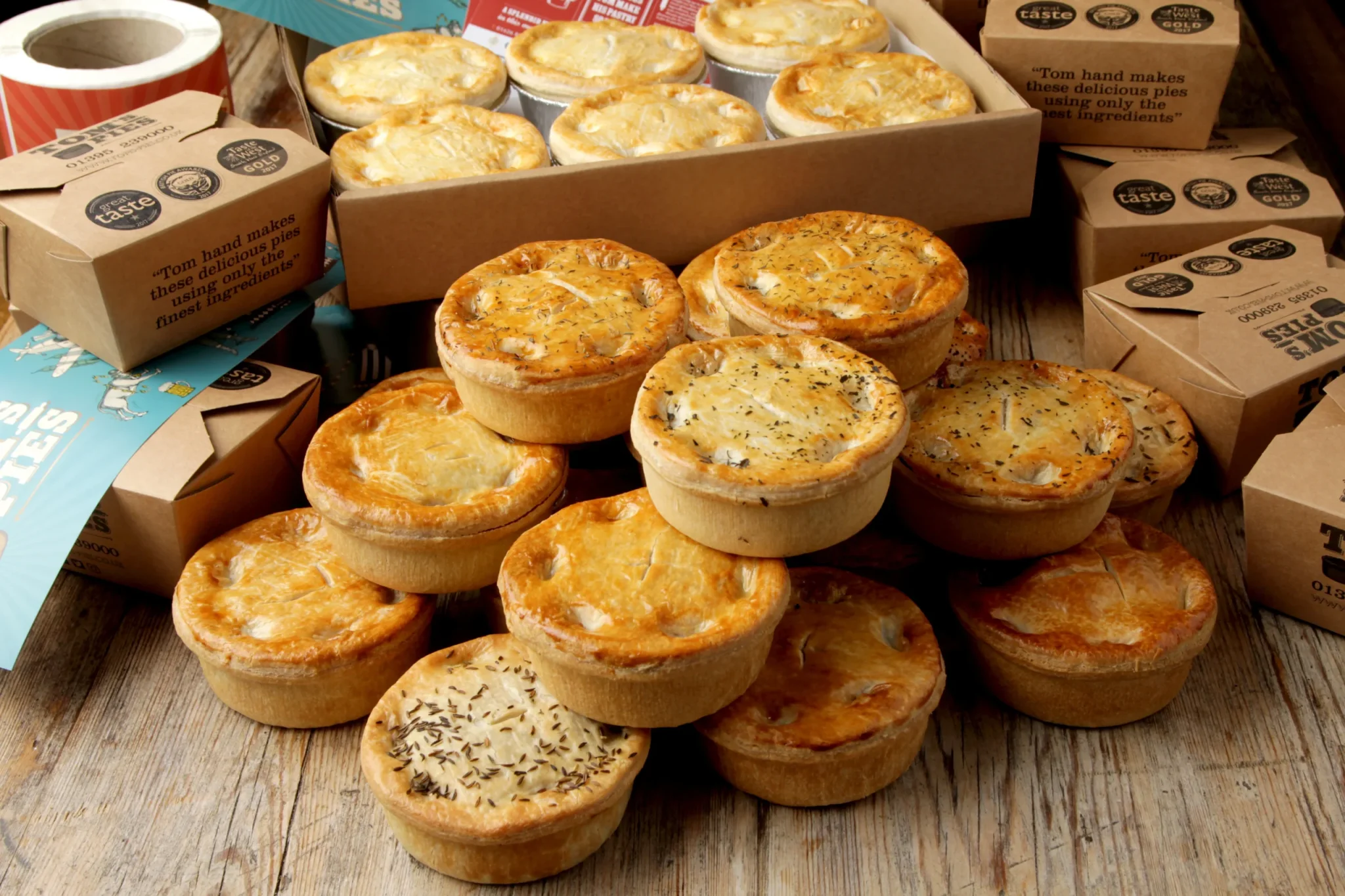 Display of golden, handmade pies in rustic packaging from Tom’s Pies, featured in a case study brochure designed by Montpellier Creative for a specialist food producer